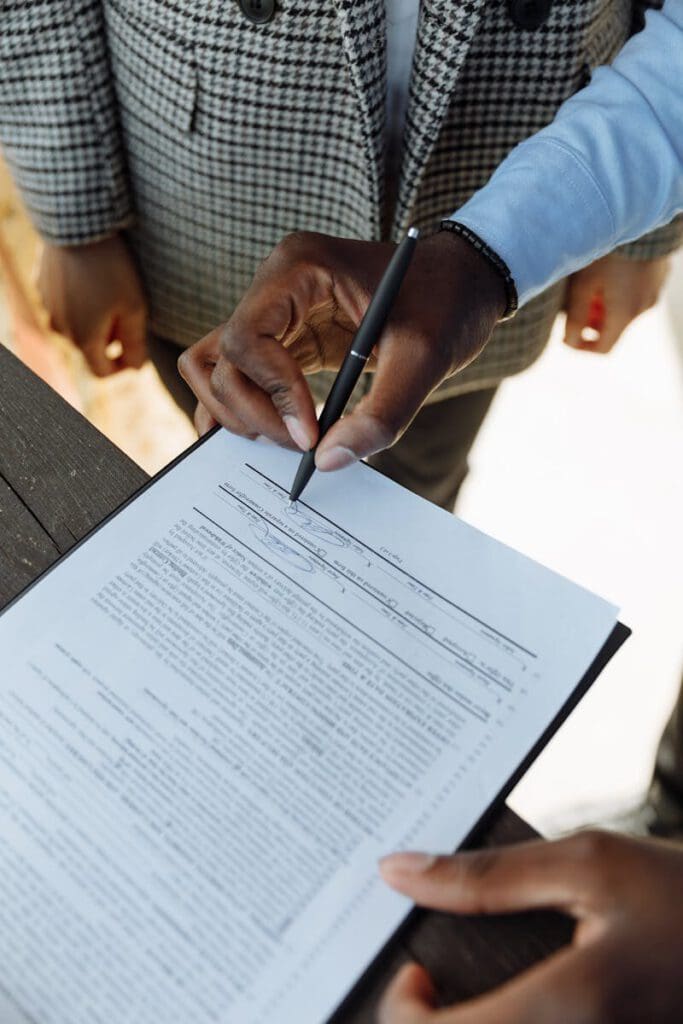Detailed view of a person signing a business contract with a pen, emphasizing agreement and ownership.